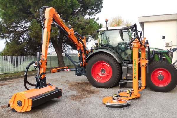 Oversized straddle brush cutter for mowing around obstacles, with central tractor hitch